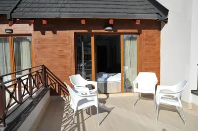 a balcony with white chairs and a bed at Milmari Resort - Lux Apartment in Kopaonik