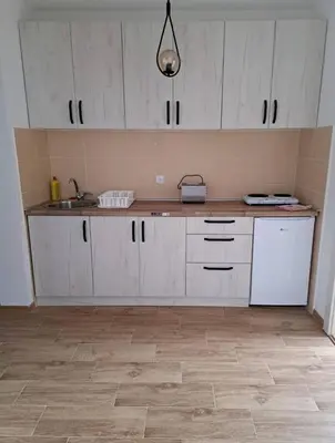 a kitchen with white cabinets and a wooden floor at Talija Apartman in Vrnjačka Banja