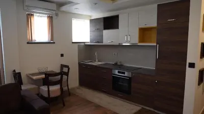 a kitchen with wooden cabinets and a table and a stove at Bella apartments in Kruševac