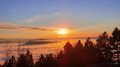 a sunset over the ocean with trees and clouds at Kraljev Konak in Kopaonik