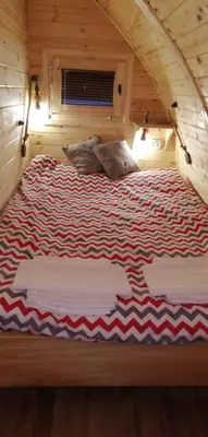 a large bed in a log cabin with two pillows at Vila Jelena - BUNGALOV in Crni Vrh