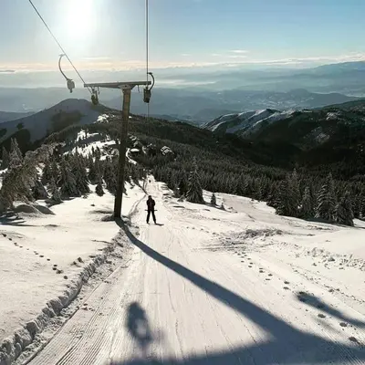 a person riding a ski lift on a snow covered mountain at Apartman Kalina Suncani Breg in Kopaonik