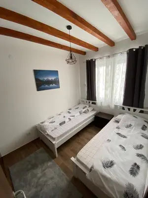 two beds in a room with white walls and wooden ceilings at Apartman 24 - Vila Montana Kopaonik in Kopaonik