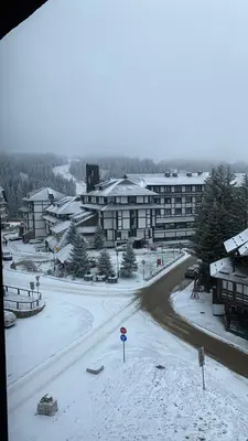 a snow covered street in front of a building at Apartman 24 - Vila Montana Kopaonik in Kopaonik