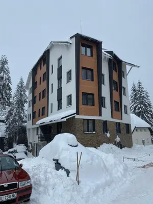 a car parked in front of a building covered in snow at Apartman 24 - Vila Montana Kopaonik in Kopaonik