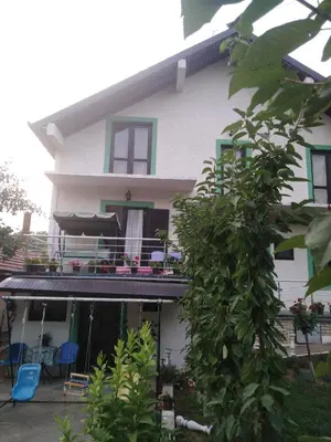 a white house with a balcony with blue chairs at Snezana home in Vranje