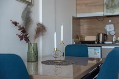 a kitchen with a table with two candles and blue chairs at Apartman Klara S 23 in Kopaonik