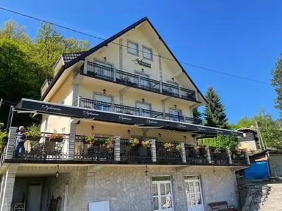 a building with balconies and flowers on it at Lužnjanin restoran i sobe in Jošanička Banja