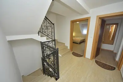 a staircase with a black iron railing in a room at Lužnjanin restoran i sobe in Jošanička Banja