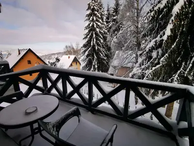 a balcony with a table and chairs in the snow at Soko lux apartman in Kopaonik