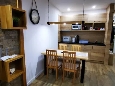 a kitchen with a table and chairs and a clock at Soko lux apartman in Kopaonik
