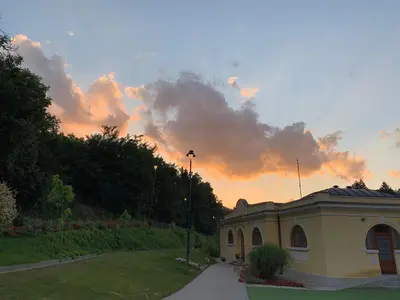 a building in a park with a sunset in the background at Apartmani Radoičić in Jošanička Banja