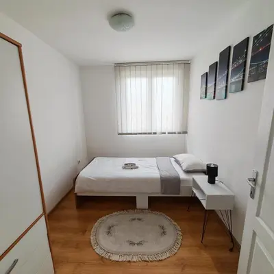 a small bedroom with a bed and a rug at Apartman - stan na dan LENJINKA in Vranje