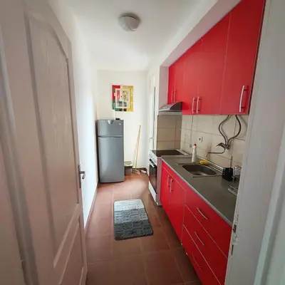 a kitchen with red cabinets and a refrigerator at Apartman - stan na dan LENJINKA in Vranje