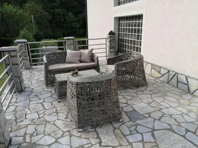 a patio with wicker chairs and tables on a building at Vila Jakovljević in Jošanička Banja