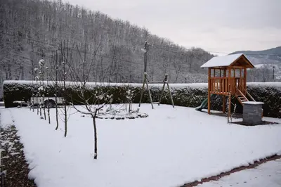 a playground in a yard covered in snow at Vila Jakovljević in Jošanička Banja