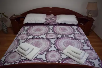 a bed with a purple and pink bedspread and white towels at Vila Jakovljević in Jošanička Banja