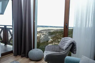 a living room with a chair and a large window at Vila Planinsko Blago in Kopaonik