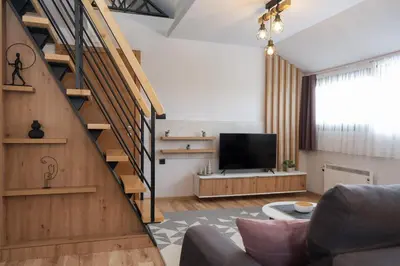 a living room with a staircase and a television at Vila Planinsko Blago in Kopaonik