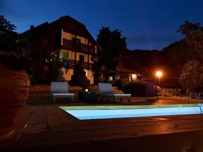 a swimming pool with two white chairs and a house at Vila Djordjevic - Priroda vas okruzuje in Brus