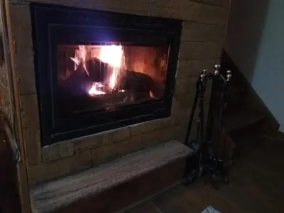 a fireplace with a fire in it with a tripod at Ema A2 Kraljevi Čardaci in Kopaonik