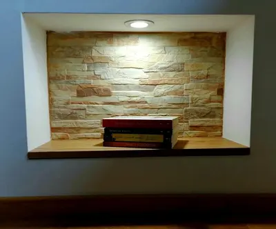 a shelf with books on it with a stone wall at Vila Irina Kopaonik - Apartman IN in Kopaonik