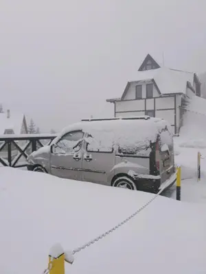 a van covered in snow in front of a house at Vila Irina Kopaonik - Apartman IN in Kopaonik