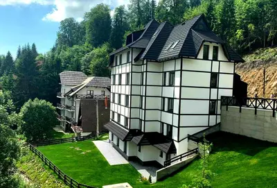 a large white house with a black roof at Vila Irina Kopaonik - Apartman IN in Kopaonik