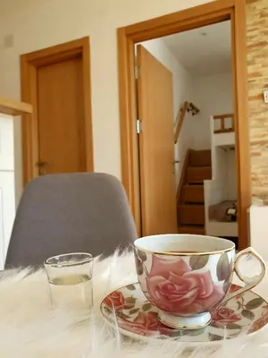 a cup on a plate with a glass on a table at Vila Irina Kopaonik - Apartman IN in Kopaonik