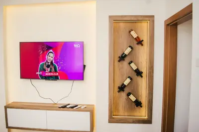 a flat screen tv hanging on a wall with wine bottles at Aparment Theatre in Niš