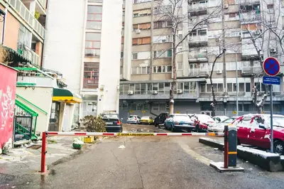 a parking lot with cars parked in front of a building at Aparment Theatre in Niš