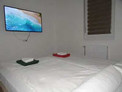 a white bed with a flat screen tv on a wall at Apartman N&N in Vrnjačka Banja