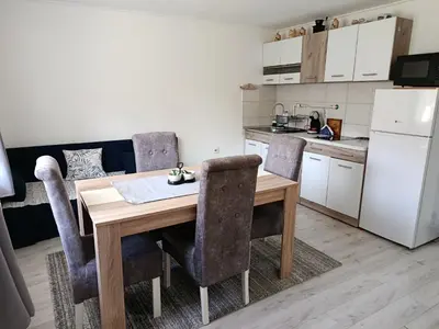 a kitchen with a wooden table and chairs in a kitchen at Apartman Branka in Niška Banja