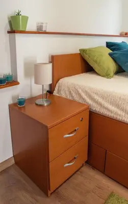 a bed with a wooden dresser with a lamp on it at Apartmani Jovčić in Leskovac