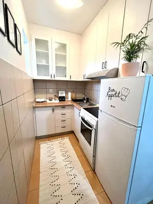 a small kitchen with white cabinets and a refrigerator at Apartment Atria in Vrnjačka Banja
