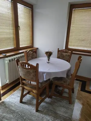 a dining room with a table and chairs and windows at Apartman Miloš in Vrnjačka Banja