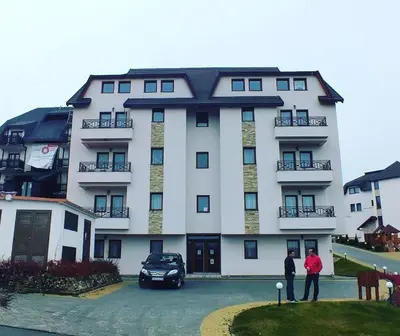 two people standing in front of a large building at Apartman D16 Milmari Kopaonik in Kopaonik