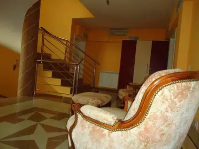 a living room with a chair and a staircase at Lux Apartmani Nikola in Vrnjačka Banja