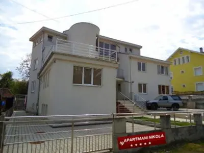 a white house with a fence in front of it at Lux Apartmani Nikola in Vrnjačka Banja