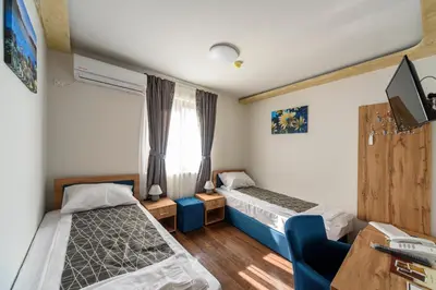 a bedroom with two beds and a tv and a window at Garni Hotel Mala Moskva in Bela Palanka
