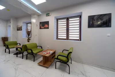 a waiting room with green chairs and a table at Garni Hotel Mala Moskva in Bela Palanka