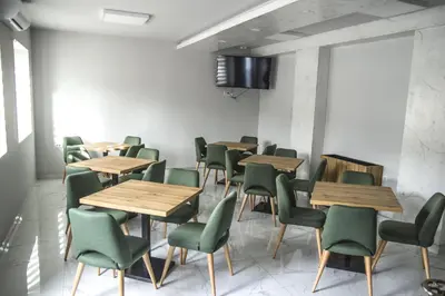 a waiting room with wooden tables and green chairs at Garni Hotel Mala Moskva in Bela Palanka