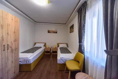 a room with two beds and a chair and a window at Garni Hotel Mala Moskva in Bela Palanka
