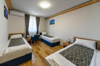 a bedroom with two beds and a desk and a chair at Garni Hotel Mala Moskva in Bela Palanka