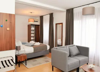 a bedroom with a bed and a couch and a chair at MILA in Vrnjačka Banja