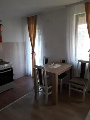 a dining room with a table and chairs and a kitchen at Stan KALA in Vrnjačka Banja