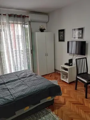 a bedroom with a bed and a chair and a cabinet at Apartman JELENA M Vrnjačka Banja in Vrnjačka Banja
