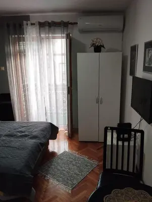 a bedroom with a bed and a cabinet and a rug at Apartman JELENA M Vrnjačka Banja in Vrnjačka Banja