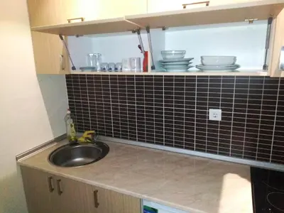 a kitchen with a sink and a black tile wall at Apartman NIKOLIJA Vrnjačka Banja in Vrnjačka Banja