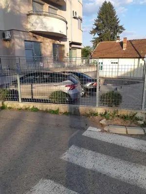a fence with a car parked next to a house at Apartman NIKOLIJA Vrnjačka Banja in Vrnjačka Banja